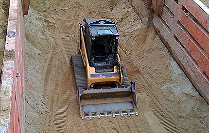 Skid steer working inside the trench box